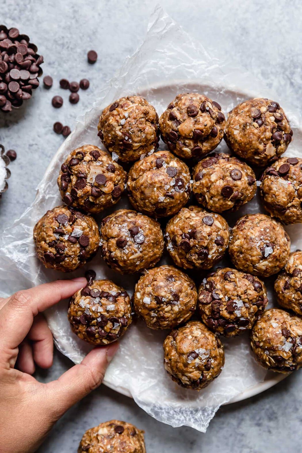 Peanut Butter Oatmeal Balls on a platter with a hand grabbing one of the bites.