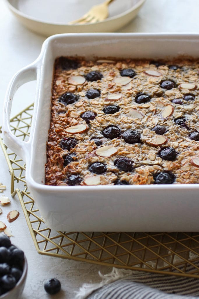 Blueberry Baked Oatmeal in a white baking dish right out of the oven sitting on a gold wire cooling rack.
