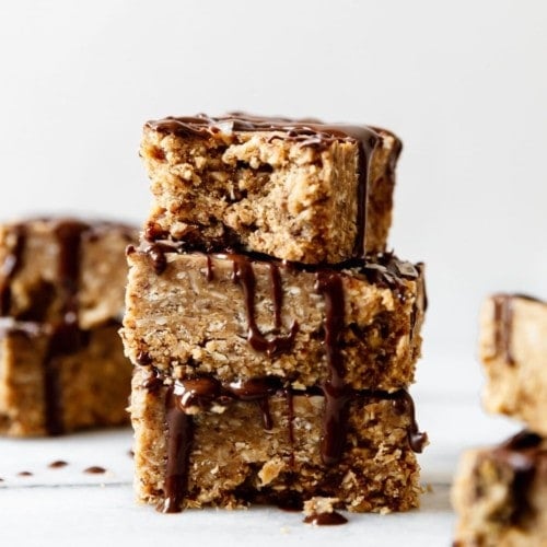 Three mini peanut butter protein bars stacked on each other drizzled with dark chocolate