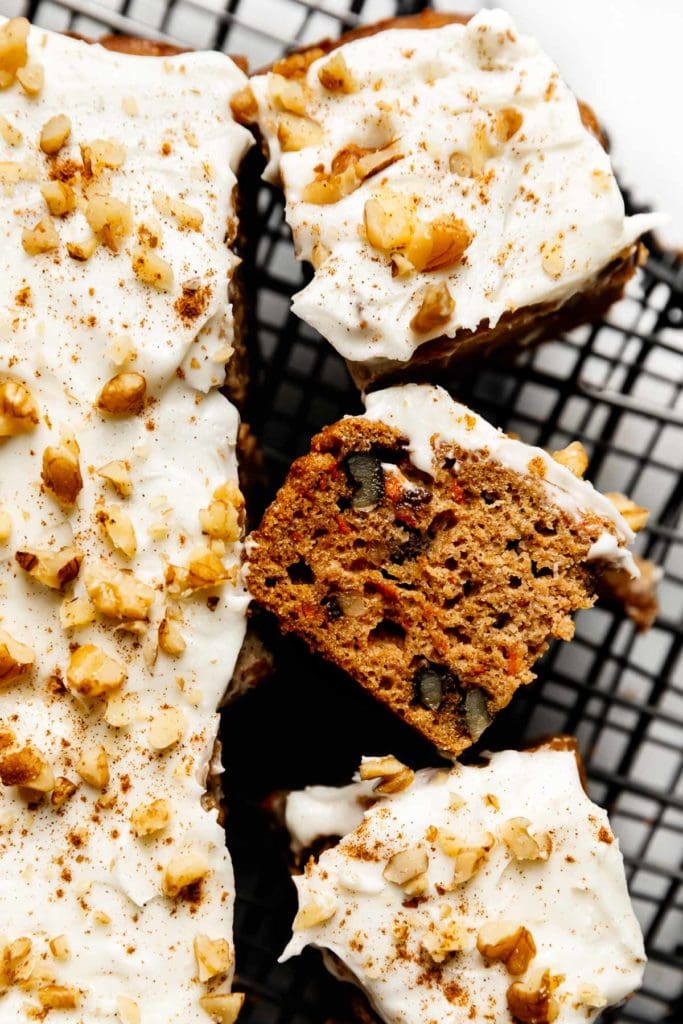 Healthy carrot cake bars topped with cream cheese frosting, cut into bars on a cooling rack