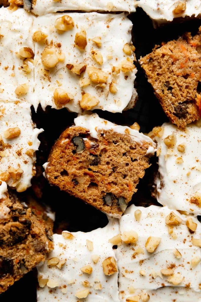 Healthy gluten-free carrot cake with cream cheese frosting cut into pieces and laying on their side to show texture
