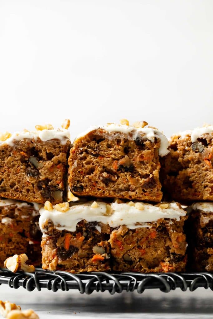 Gluten-free carrot cake bars with cream cheese frosting cut into bars and stacked on top of each other