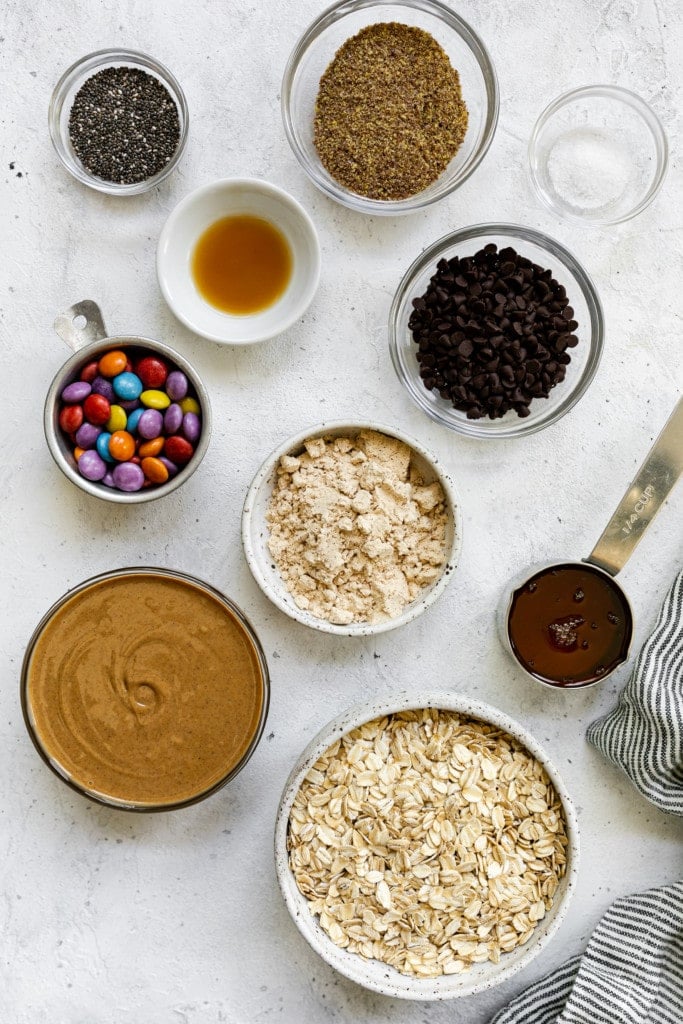 All ingredients for monster cookie peanut butter protein bites in small bowls and measuring cups on a countertop in an overhead shot. 