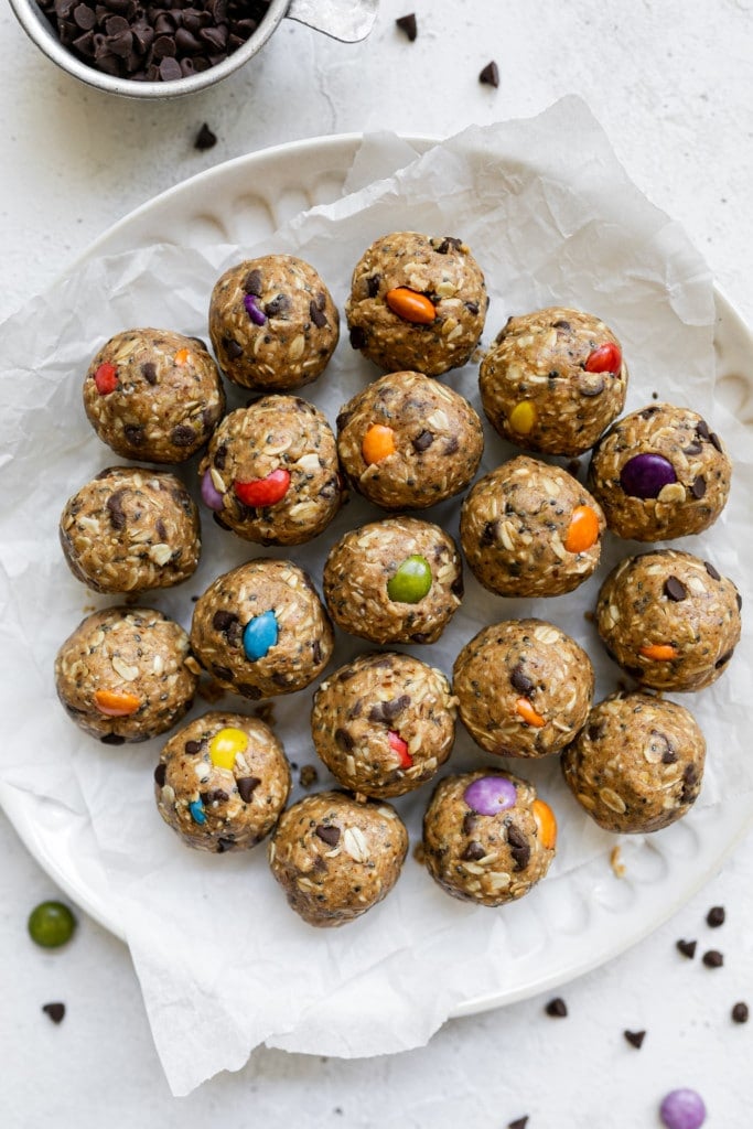 Overhead view of monster cookie peanut butter protein balls with colorful candy coated chocolate pieces in each ball. Plated on a parchment covered plate. 