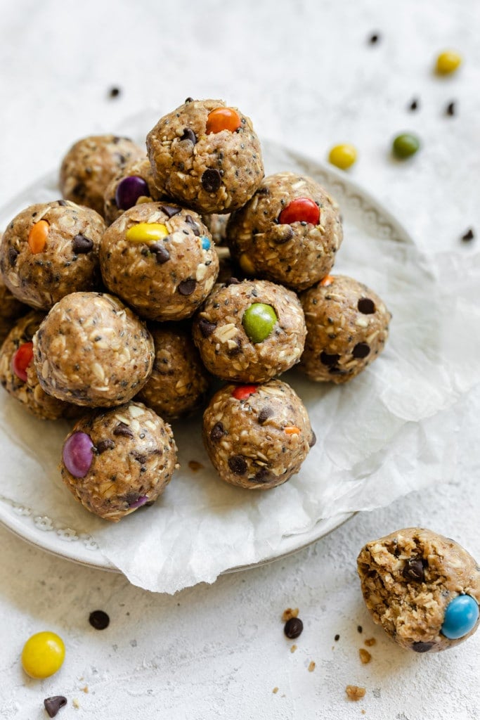 A pyramid stack of monster cookie peanut butter protein balls on a parchment covered plate. 