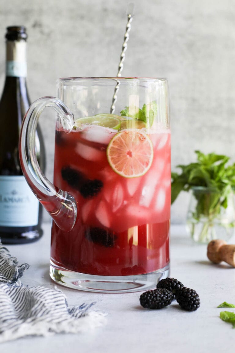 Tall pitcher of blackberry lime prosecco cocktails.