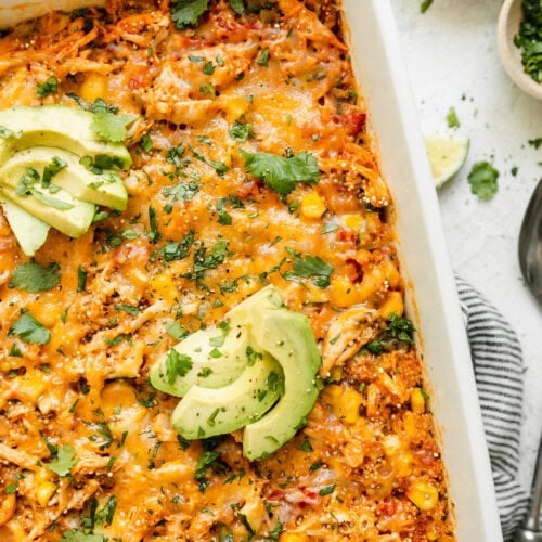 Overhead view chipotle quinoa casserole with chicken in a white baking dish topped with melted cheese.