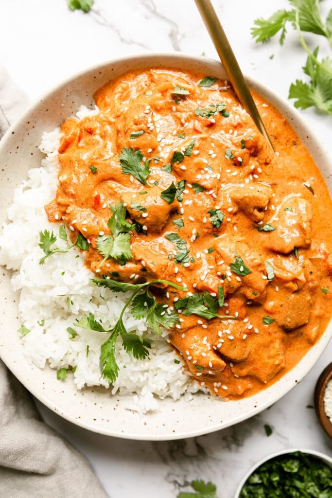 Stone bowl with serving of Creamy crockpot butter chicken served with white rice.