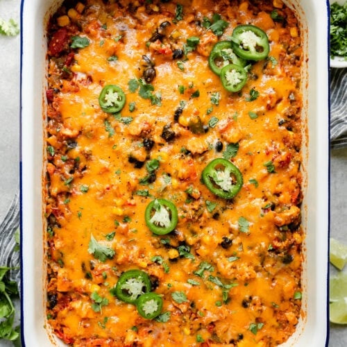 Overhead view chicken quinoa casserole in baking dish topped with melted cheddar cheese.